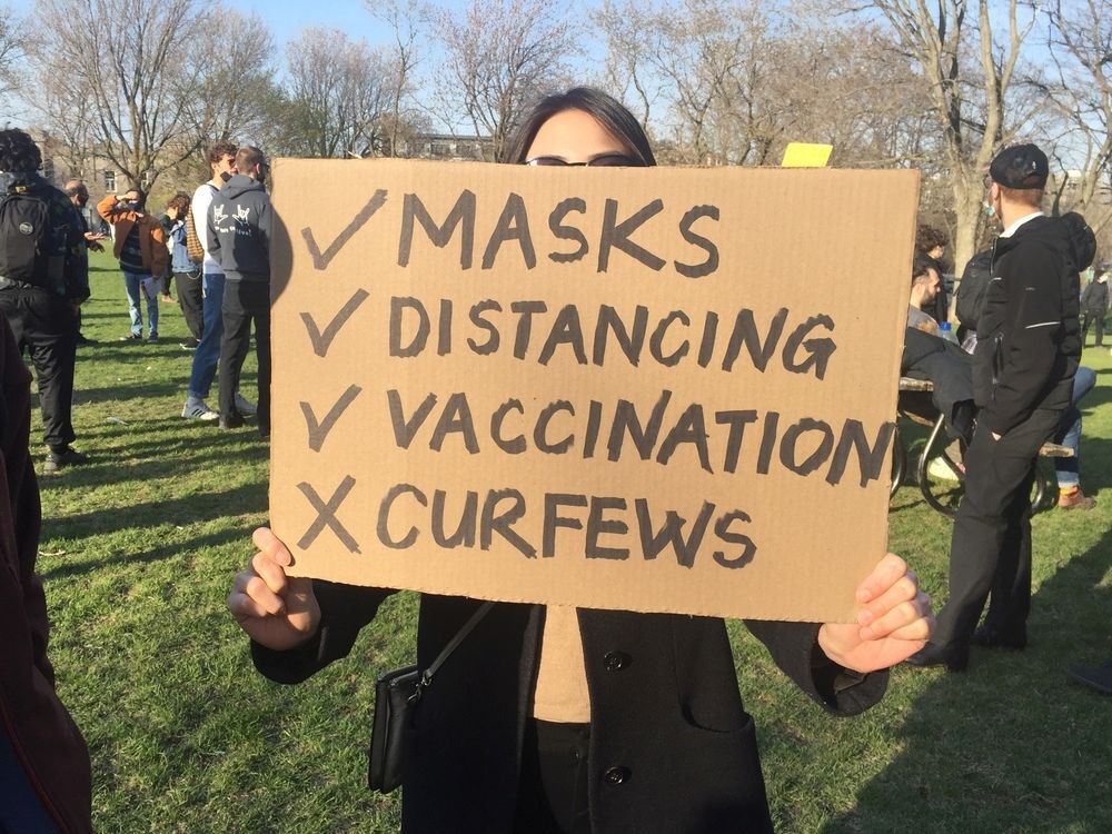 Maggie, a protester at Jeanne-Mance Park, holds a poster expressing her opposition to curfews during a protest on Sunday, April 18, 2021.