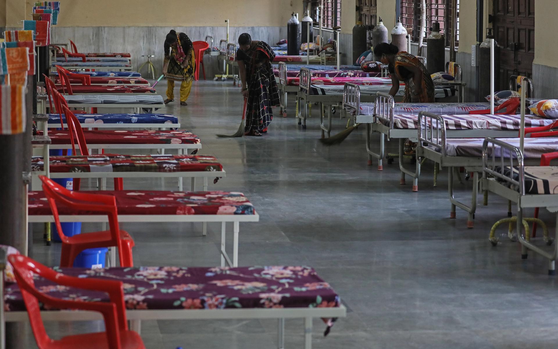 Workers clean the floor near the beds inside a newly opened Covid-19 centre in Mumbai. EPA