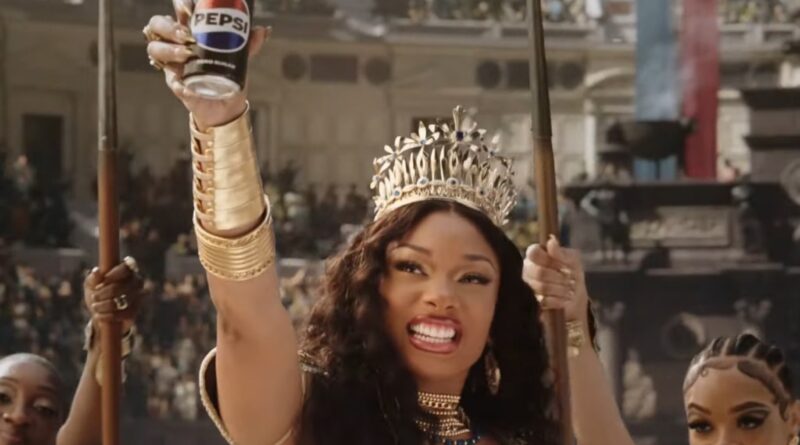 Megan Thee Stallion Reimagines Queen’s ‘We Will Rock You’ for ‘Gladiator’-Themed Ad With Travis Kelce